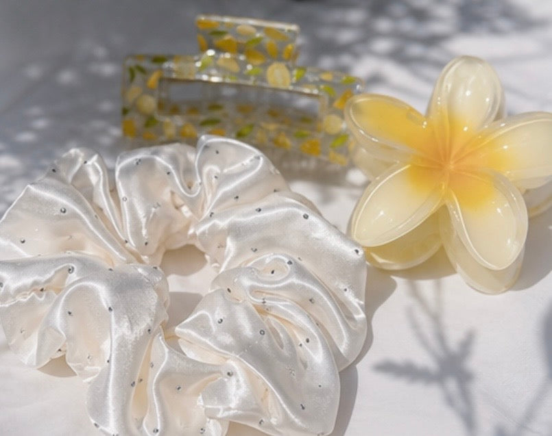 Lemon hair set detail – white dotted scrunchie, lemon claw clip and yellow flower clip on grey background – Lande Accessories